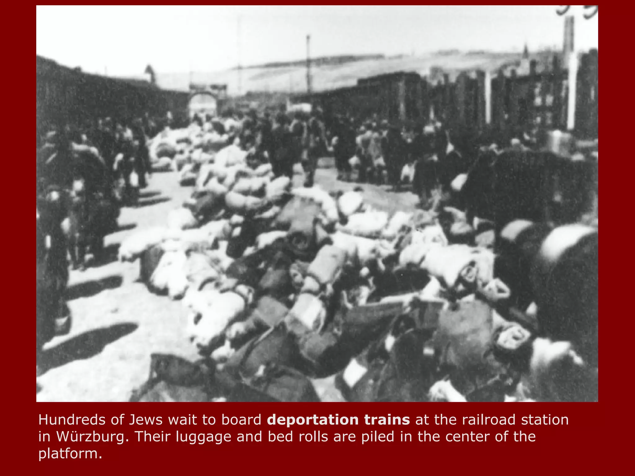 Hundreds of Jews wait to board  deportation   trains  at the railroad station in Würzburg. Their luggage and bed rolls are piled in the center of the platform.  