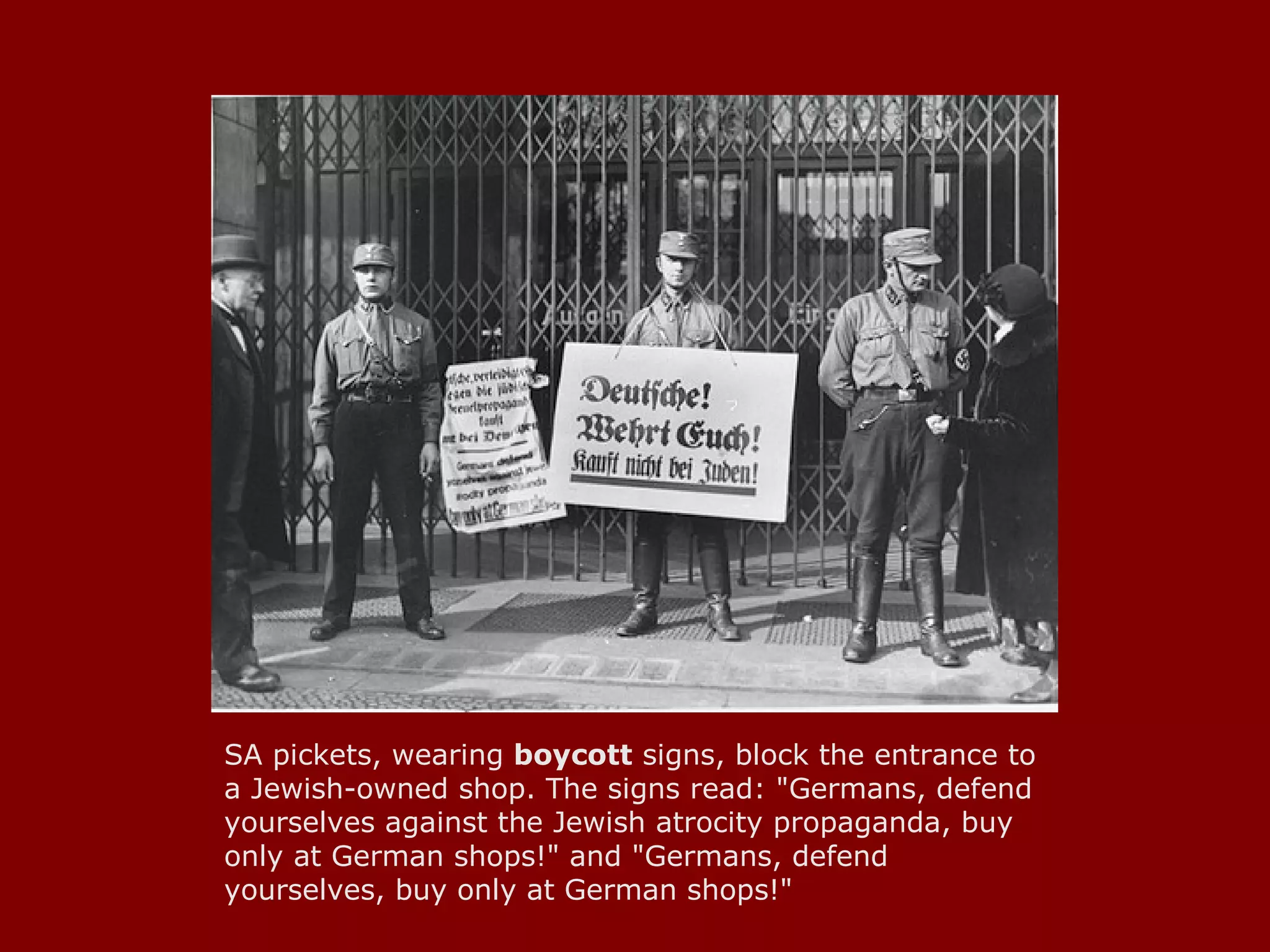 SA pickets, wearing  boycott  signs, block the entrance to a Jewish-owned shop. The signs read: "Germans, defend yourselves against the Jewish atrocity propaganda, buy only at German shops!" and "Germans, defend yourselves, buy only at German shops!"  