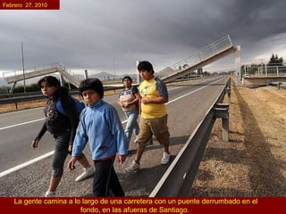 La gente camina a lo largo de una carretera con un puente derrumbado en el fondo, en las afueras de Santiago.   Febrero  27, 2010 