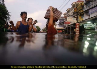 Residents wade along a flooded street on the outskirts of Bangkok, Thailand
 