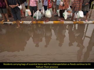 Residents carrying bags of essential items wait for a transportation as floods continue to hit
                                  Pathum Thani province
 