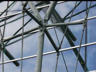 Suspended glass skins form a composite system of glass and stainless
steel. Here, glass panels are glued together with silicone and supported by
lightweight cable beams.
Typically, the lateral wind pressure is carried by the glass panels in bending
to the suspended vertical cable support structures that act as beams. The
tensile beams are laterally stabilized by the glass or braced by stainless
steel rods.
The dead loads are usually transferred from the glass panels to vertical
tension rods, or each panel is hung directly from the next panel above; in
other words, the upper panels carry the deadweight of the lower panels in
tension.
The structural and thermal movements in the glass wall are taken up by the
resiliency of the glass-to-glass silicone joints and, for example, by ball-
jointed metal links at the glass-to-truss connections, thereby preventing
stress concentrations and bending of the glass at the corners.
 