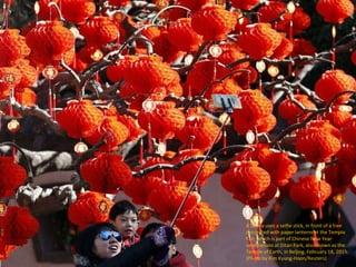 A family uses a selfie stick, in front of a tree
decorated with paper lanterns at the Temple
Fair, which is part of Chines...