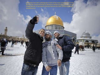 Palestinian men take a photograph in front of the snow-covered Dome of the
Rock on the compound known to Muslims as Noble ...