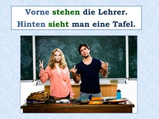 Vorne stehen die Lehrer.
Hinten sieht man eine Tafel.
 
