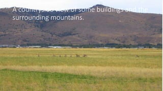 A countryside view of some buildings and the
surrounding mountains.
 