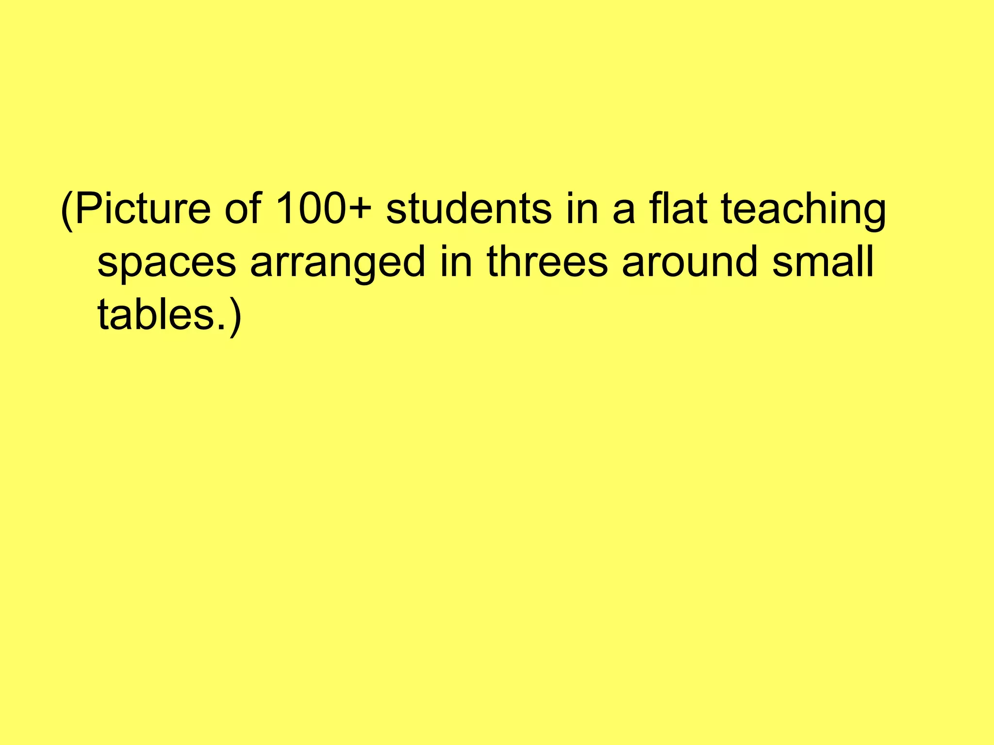 (Picture of 100+ students in a flat teaching spaces arranged in threes around small tables.) 