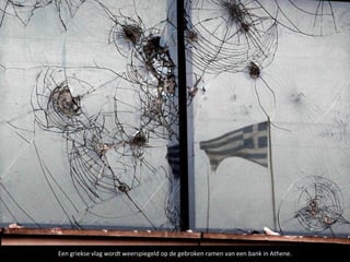 Een griekse vlag wordt weerspiegeld op de gebroken ramen van een bank in Athene.
 