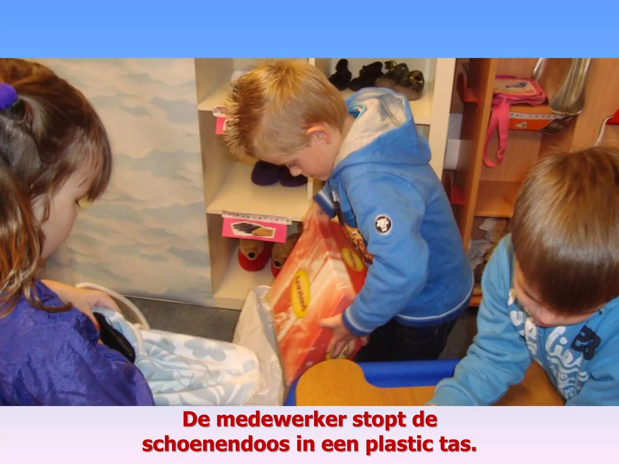 De medewerker stopt de
schoenendoos in een plastic tas.
 