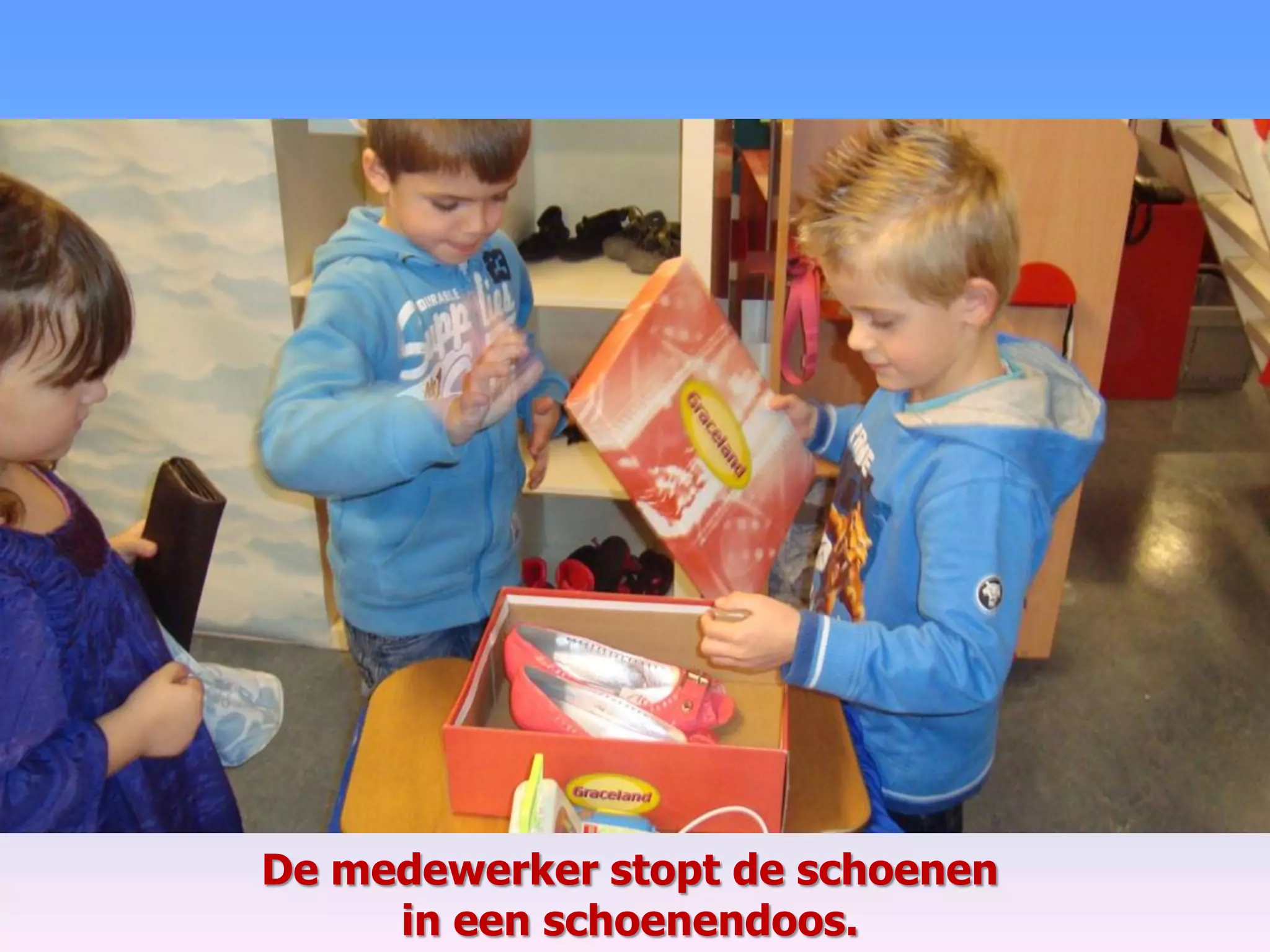 De medewerker stopt de schoenen
in een schoenendoos.
 