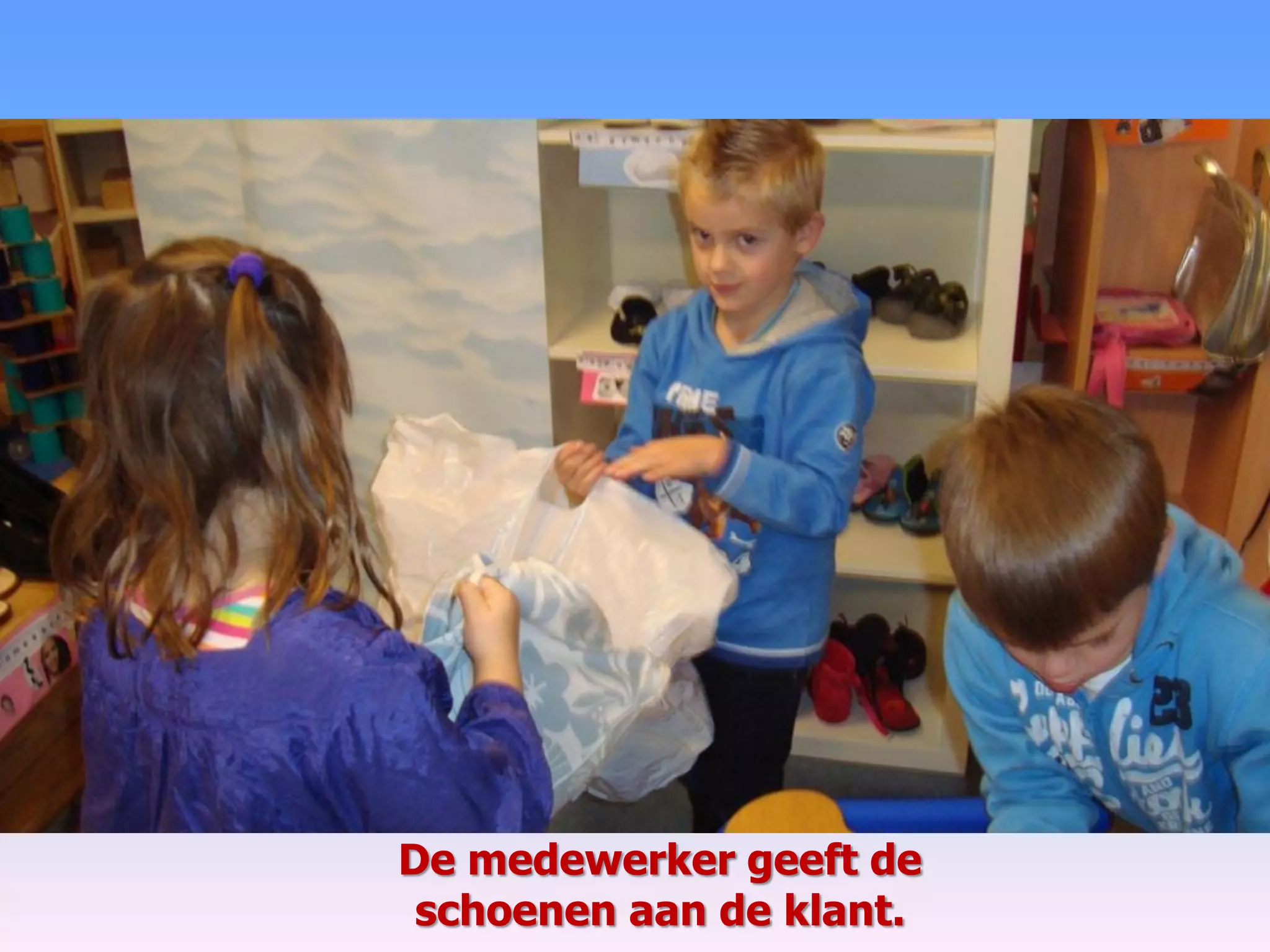 De medewerker geeft de
schoenen aan de klant.
 
