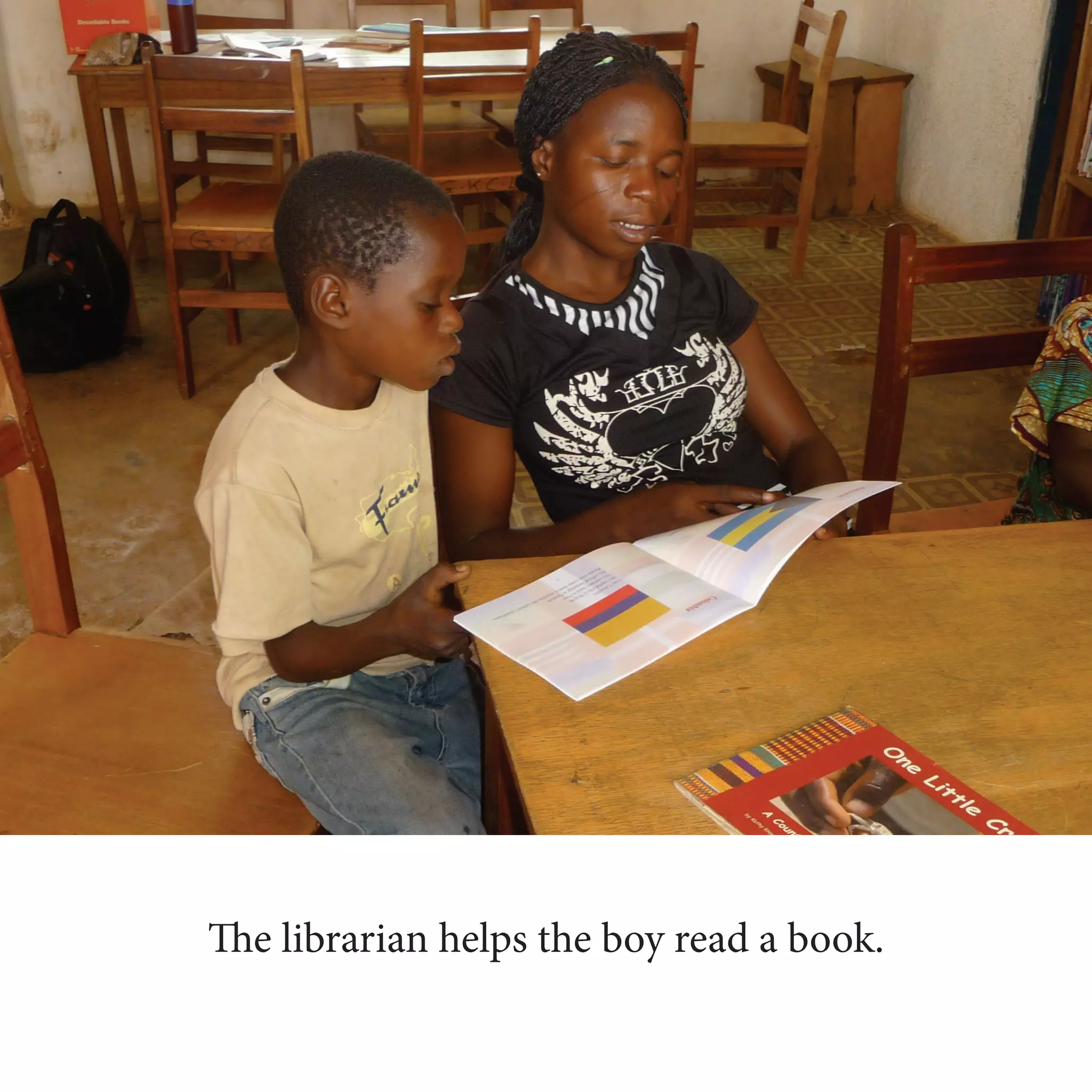 The librarian helps the boy read a book.