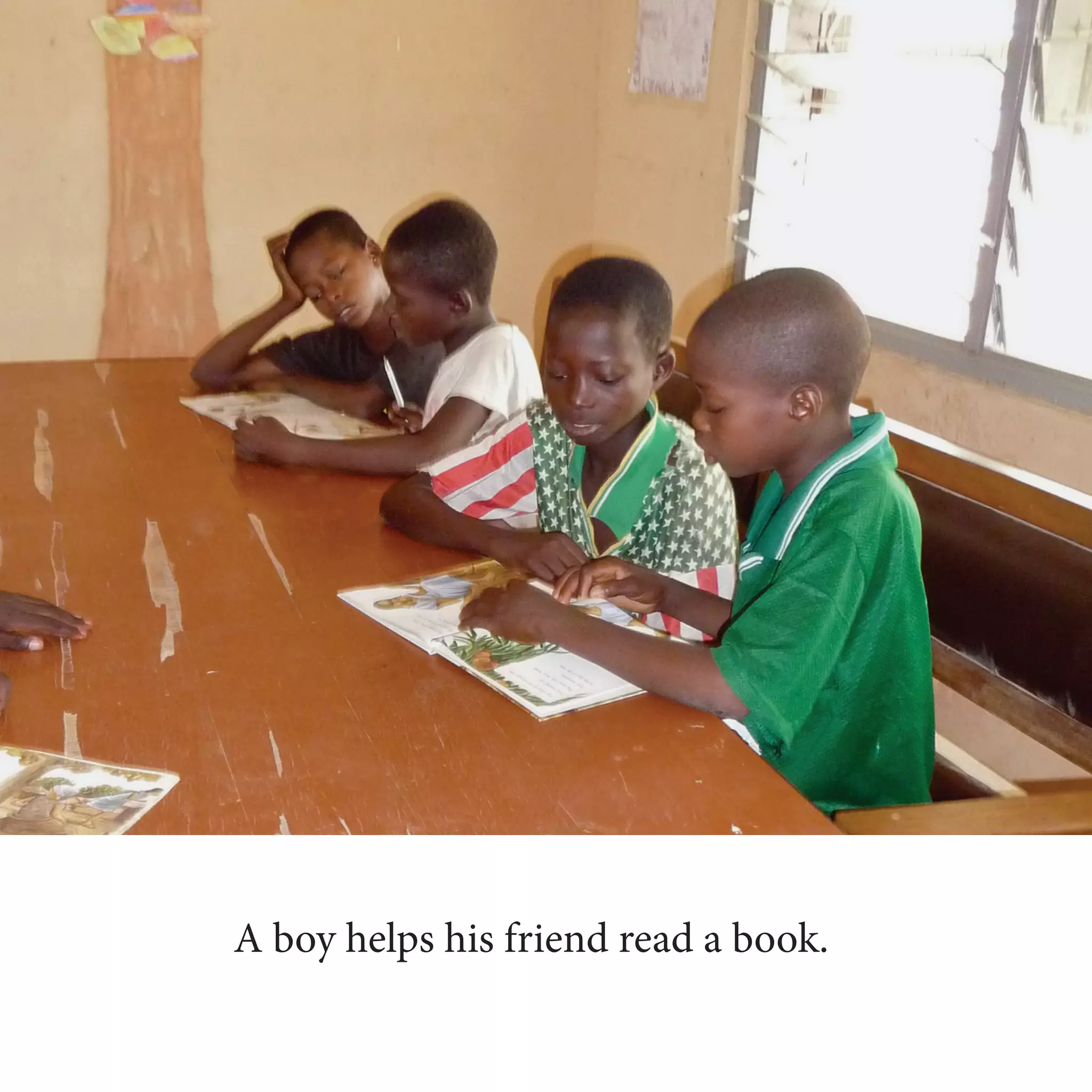 A boy helps his friend read a book.