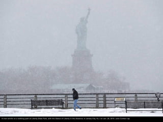 A man strolls on a walking path at Liberty State Park, with the Statue of Liberty in the distance, in Jersey City, N.J. on...