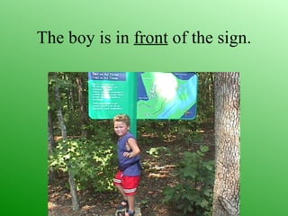 The boy is in front of the sign.